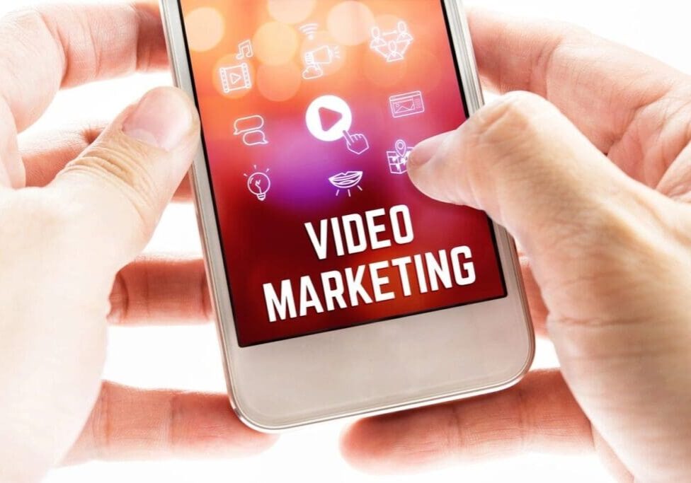 A person is holding their phone with the words video marketing on it.